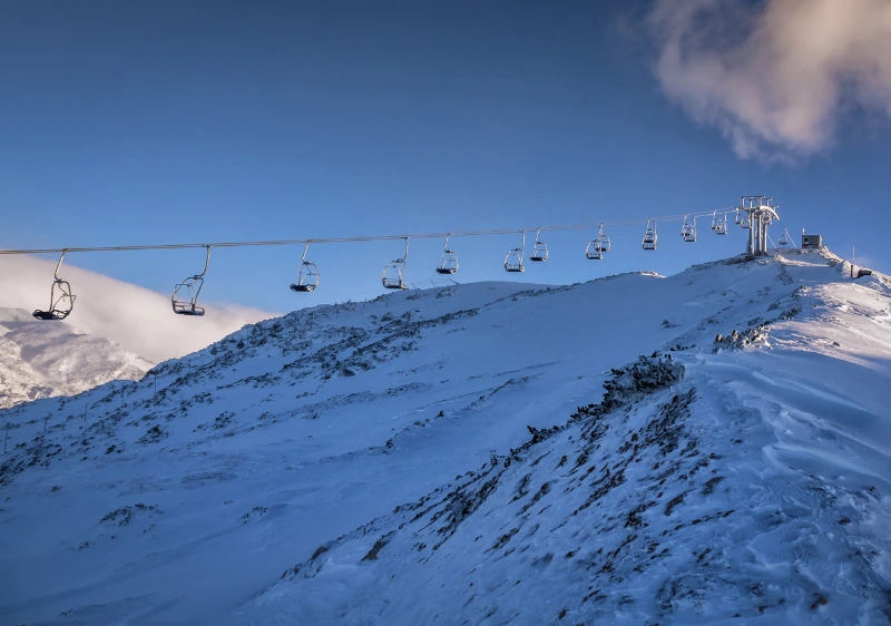 Žičnica nad zasneženo goro ob jasnem nebu